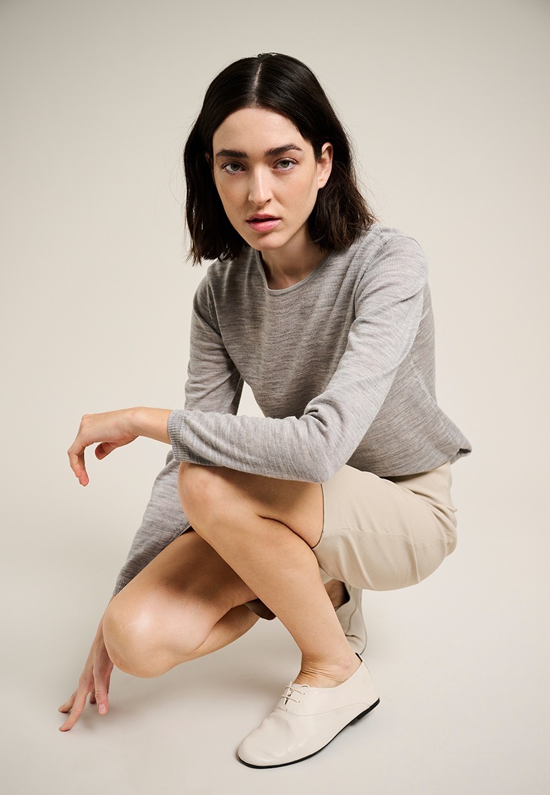 Woman wearing a light gray long-sleeve essential top from BITTE KAI RAND Essentials, styled with beige shorts and light-colored shoes.