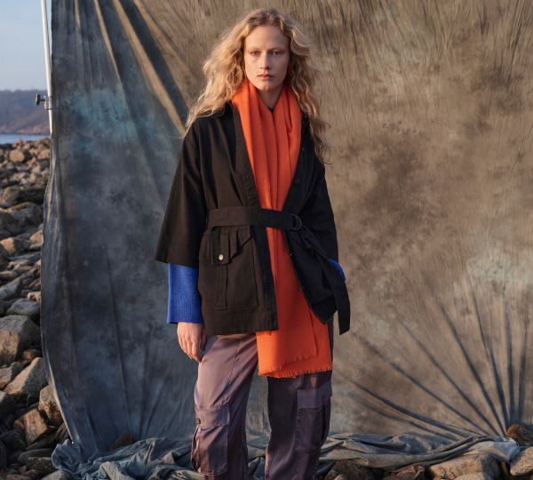 Model wearing orange scarf and black jacket