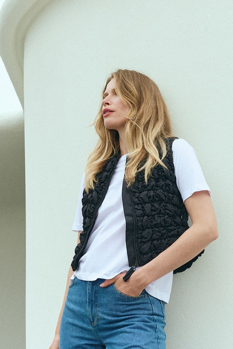 Model i hvid T-shirt og sort vest